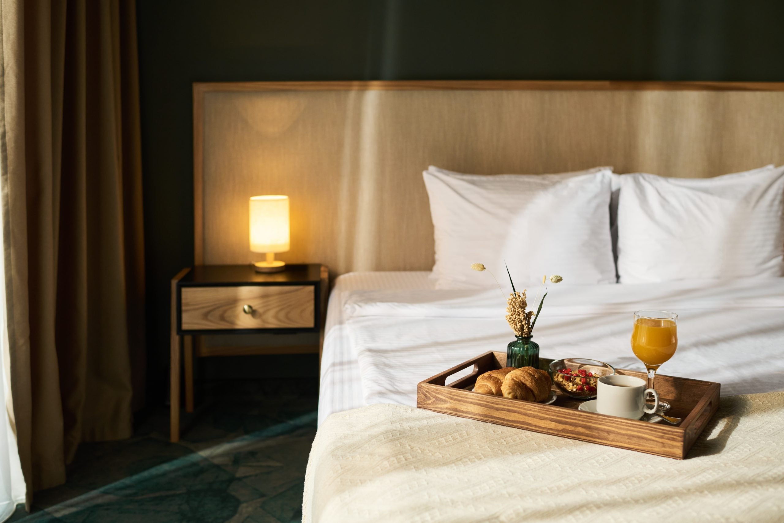 hotel bed with white bedding and breakfast and tray on the bed